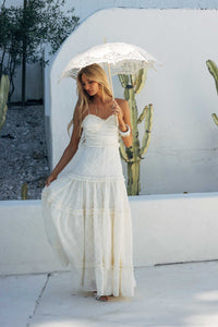 Woman in a white dress holding a lace umbrella with cacti in the background
