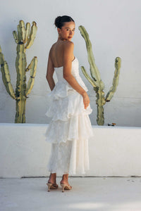 Woman in a white dress standing in front of cacti against a white wall