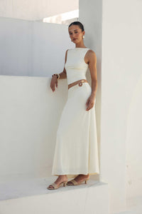 Woman in a white dress standing against a white wall