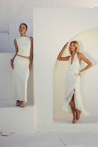 Two women in white dresses posing against a white background