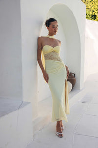 Woman in a yellow evening gown standing against a white wall with arches.