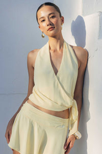 Woman wearing a light yellow outfit against a white wall