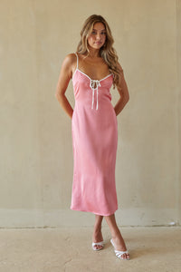 Woman wearing a pink slip dress against a plain background