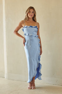 blue-image | Woman wearing a light blue dress with ruffled details against a plain background