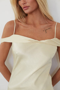 Woman wearing a light-colored dress with thin straps against a plain background