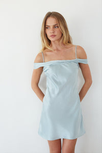 blue-image | Woman wearing a light blue off-shoulder dress against a white background