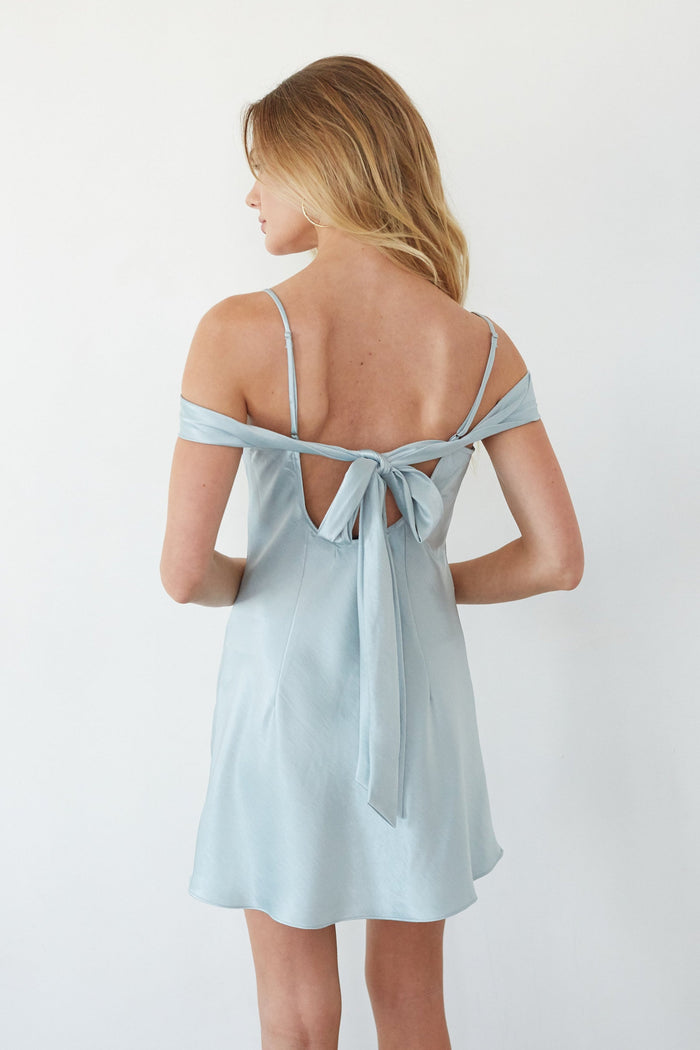 Light blue dress with thin straps and a bow detail on a white background