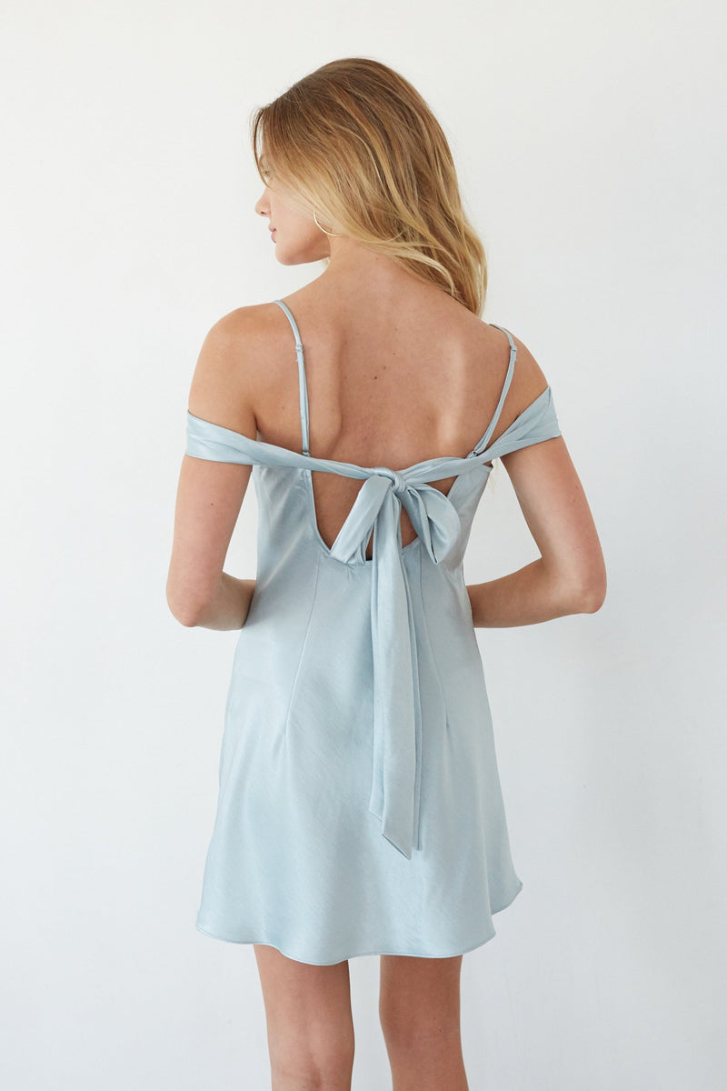 Light blue dress with thin straps and a bow detail on a white background