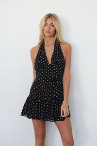 Woman wearing a black polka dot dress against a white background