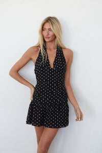 Woman wearing a black polka dot dress against a white background
