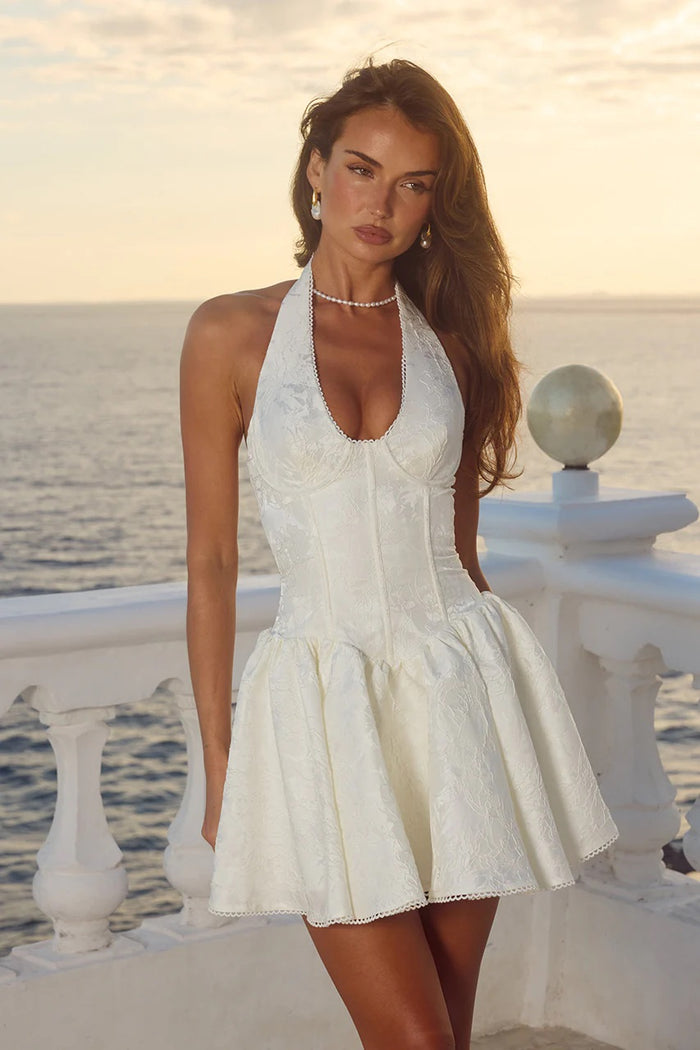 white-image | Woman in a white dress standing by a railing with a scenic background