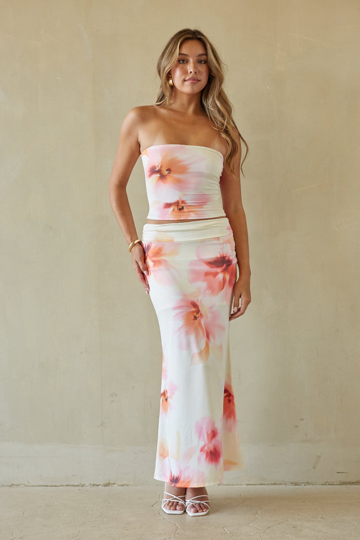 Woman wearing a strapless floral dress against a plain background