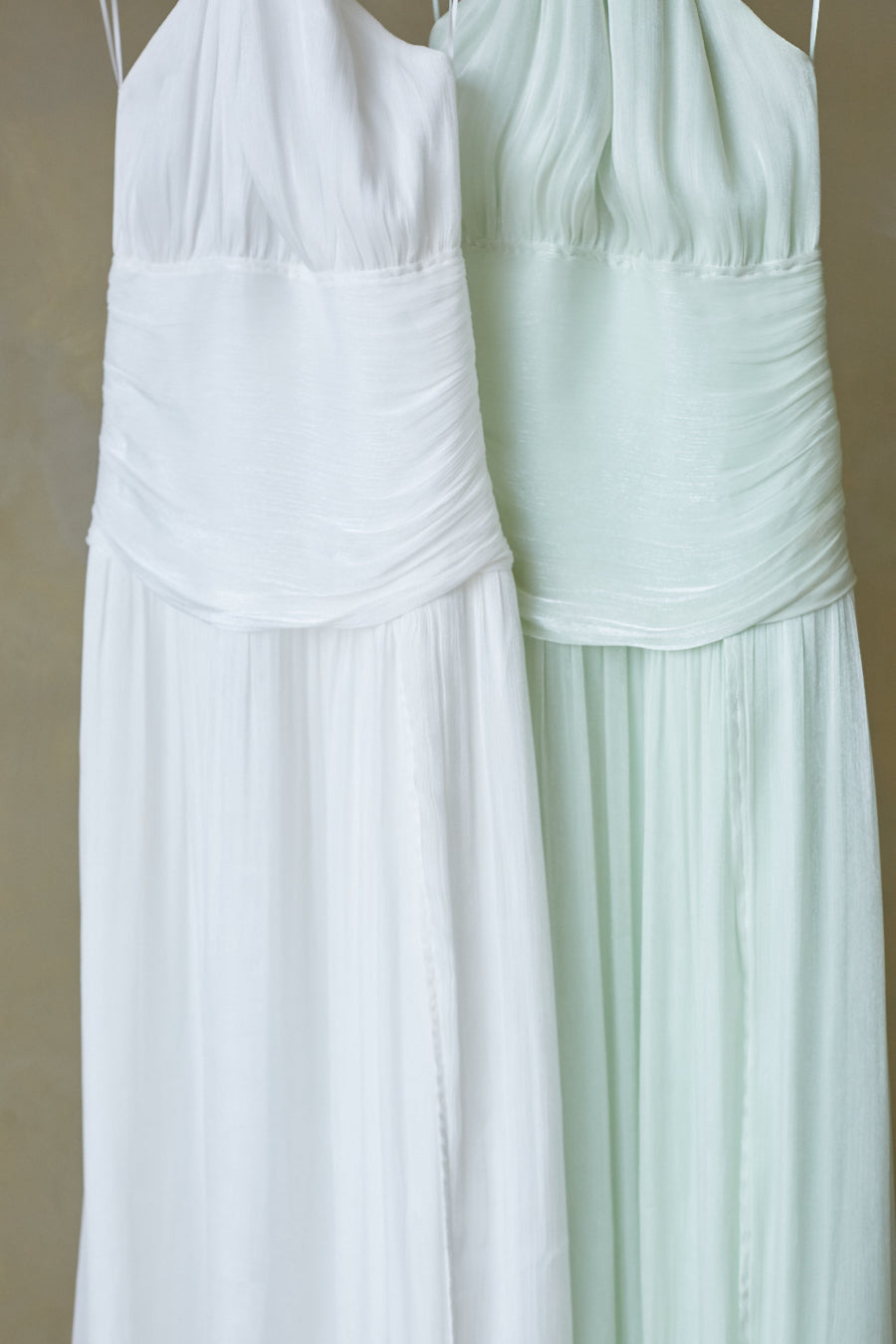 Two white dresses, one plain and one with a subtle pattern, on a beige background.