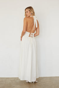 Woman wearing a white dress with cut-out back design on a plain background