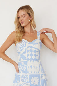 Woman wearing a light blue and white patterned dress against a plain background