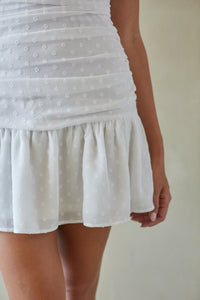 White polka dot skirt worn by a person on a plain background