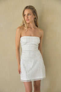 white-image | Woman wearing a white strapless dress against a beige background