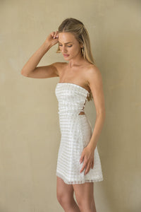 Woman wearing a white strapless dress against a beige background