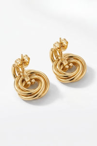 A pair of gold-toned statement earrings with a textured, twisted spiral design and butterfly backings, displayed on a clean white background.