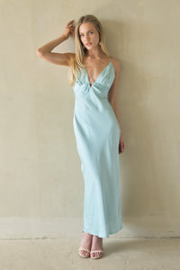 green-image | Woman wearing a light green dress against a beige wall.