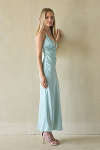 Woman wearing a light green satin dress against a plain background