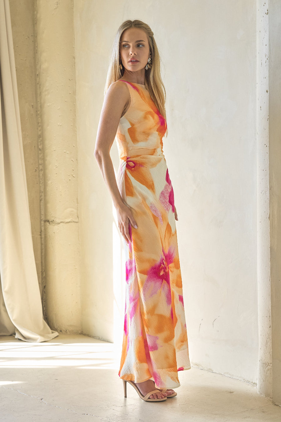 Woman wearing a colorful dress standing in a bright room with white walls and floor.