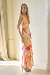 Woman wearing a colorful dress standing in a bright room with white walls and floor.