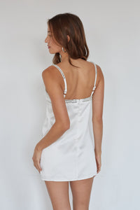 Woman wearing a white sequin-trimmed dress against a plain background