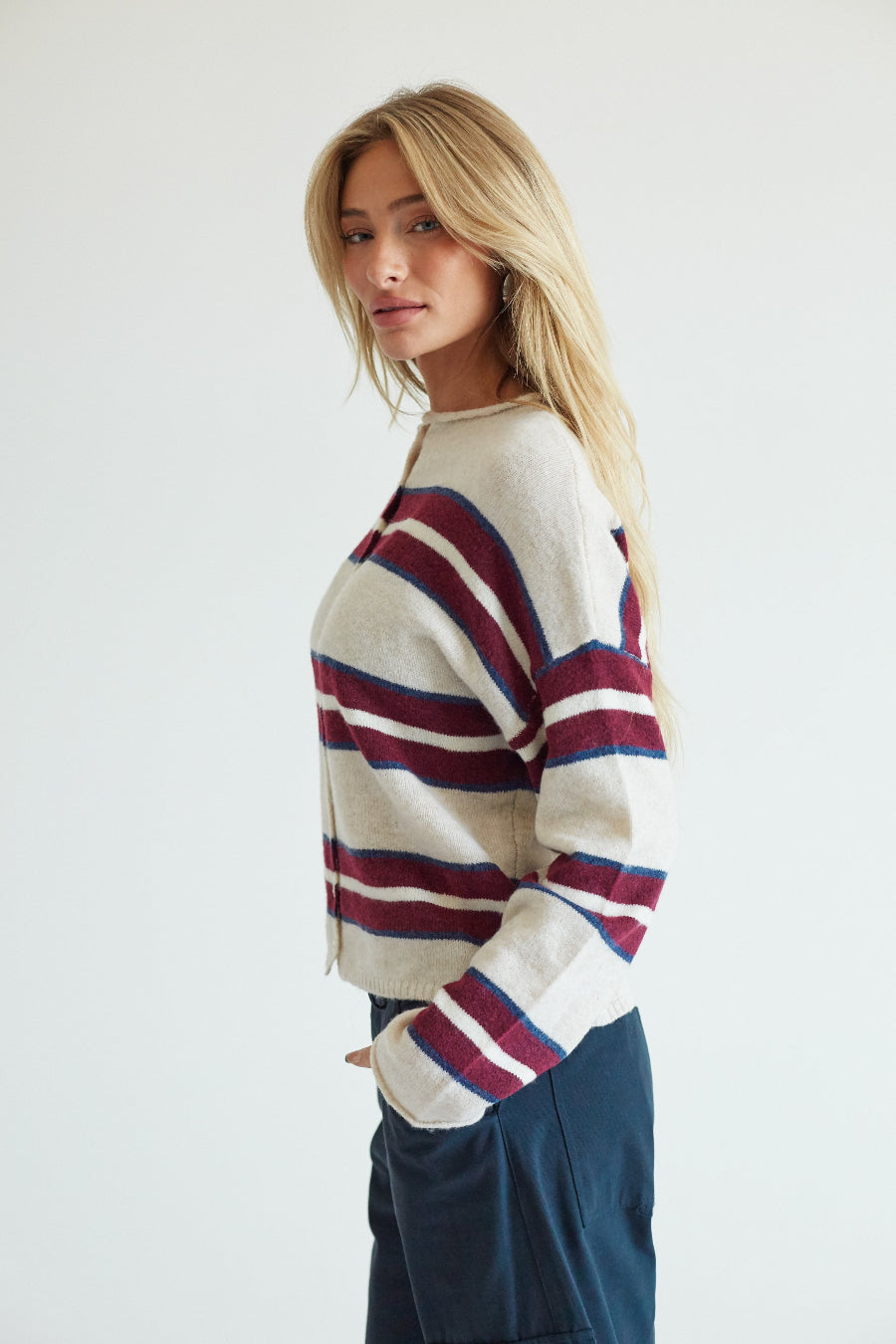 side image of a blonde model in a beige and red striped sweater