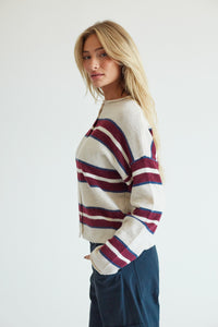 side image of a blonde model in a beige and red striped sweater