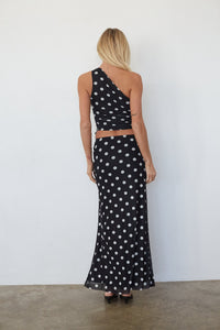 Woman wearing a black polka dot dress against a white background