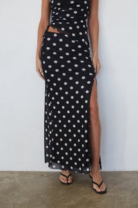 Black polka dot dress with a slit on a plain background
