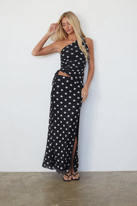 Woman wearing a black polka dot dress against a white background