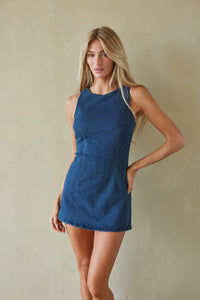 Woman wearing a blue dress against a beige wall