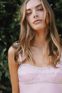 Woman wearing a pink dress with a floral pattern against a blurred green background