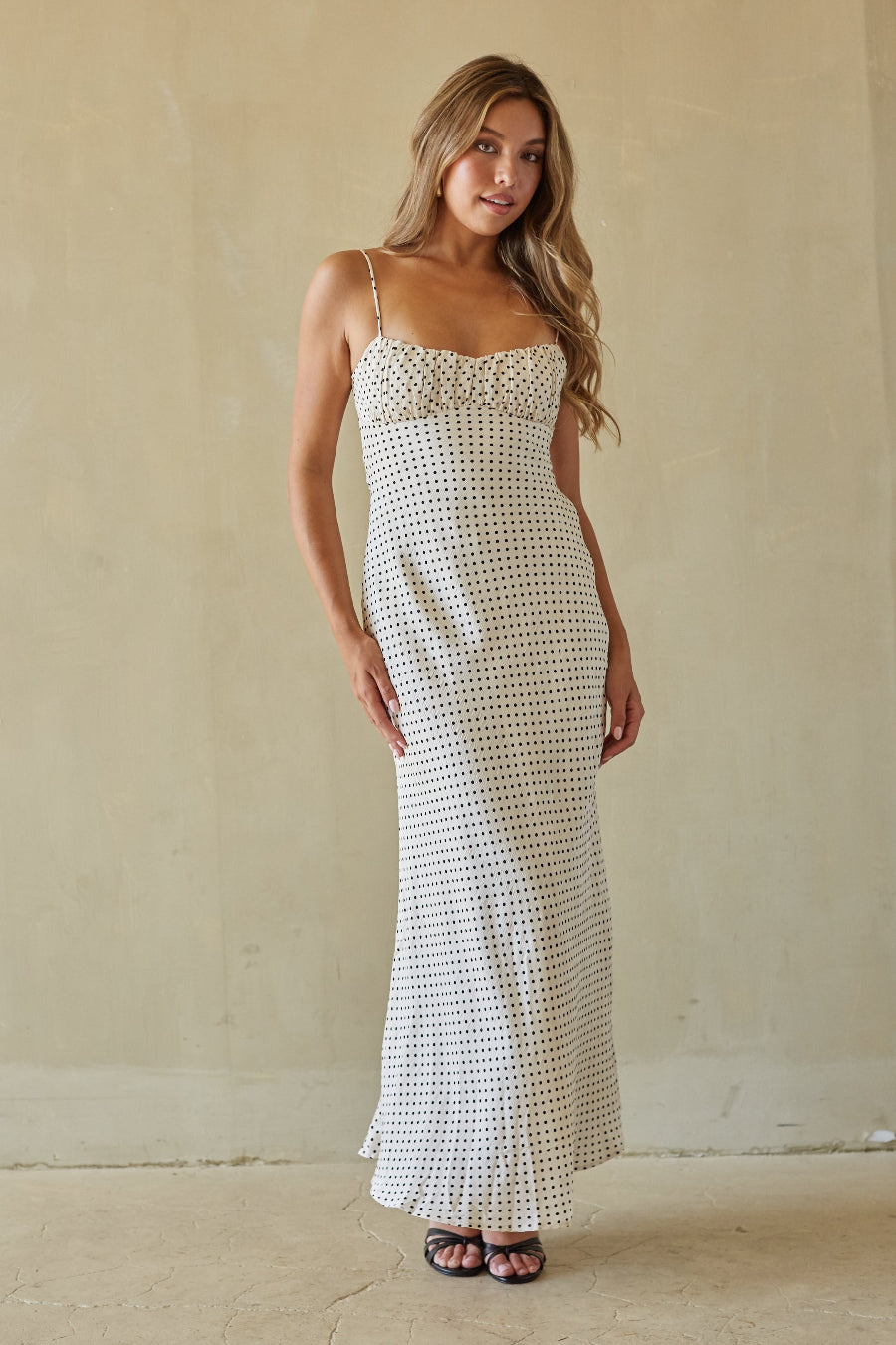 Woman wearing a white patterned dress against a plain background