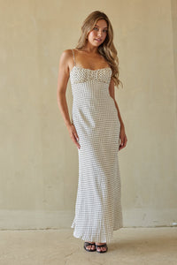 Woman wearing a white patterned dress against a plain background