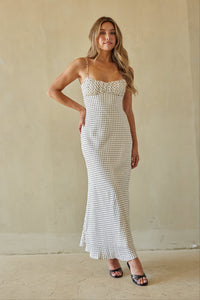 Woman wearing a white patterned dress against a beige background