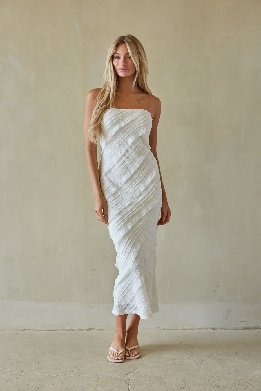 Woman wearing a white strapless dress against a plain background