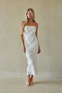 Woman wearing a white strapless dress against a plain background