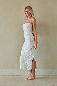 Woman wearing a white strapless dress against a plain background