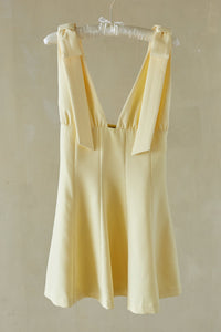 yellow-image | Yellow dress hanging on a hanger against a plain background