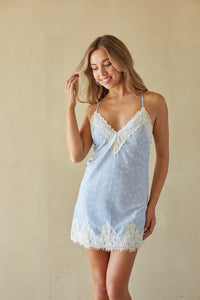 Woman wearing a light blue lace nightgown against a beige background