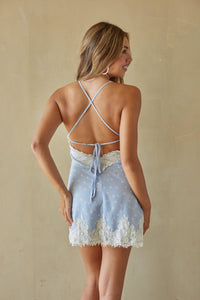 Woman wearing a light blue lace nightgown against a beige background