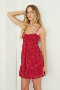 Woman wearing a red polka dot dress against a white background