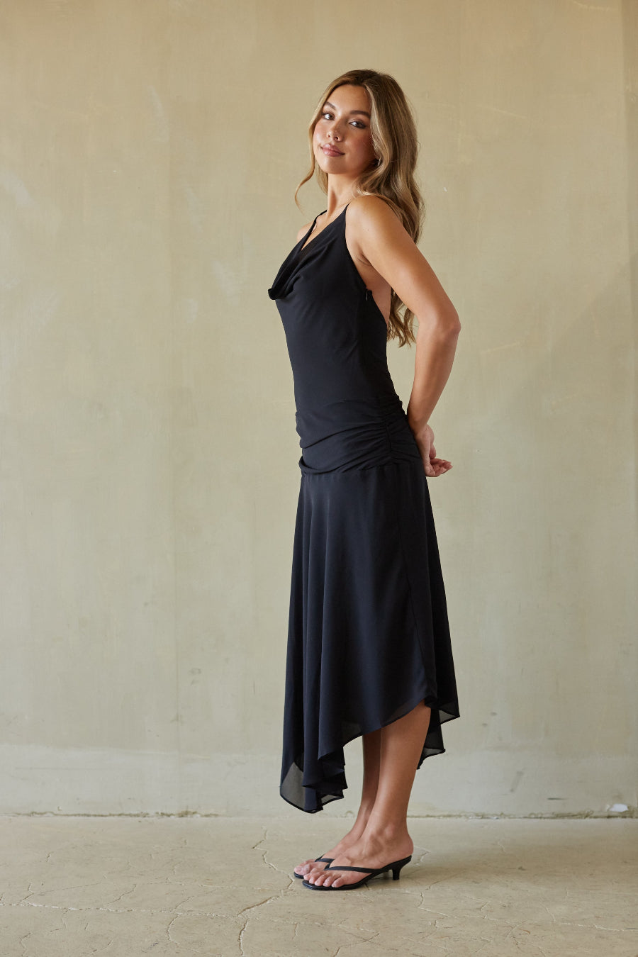 Woman wearing a black sleeveless dress against a plain background