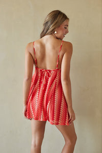 Woman wearing a red patterned dress against a beige background