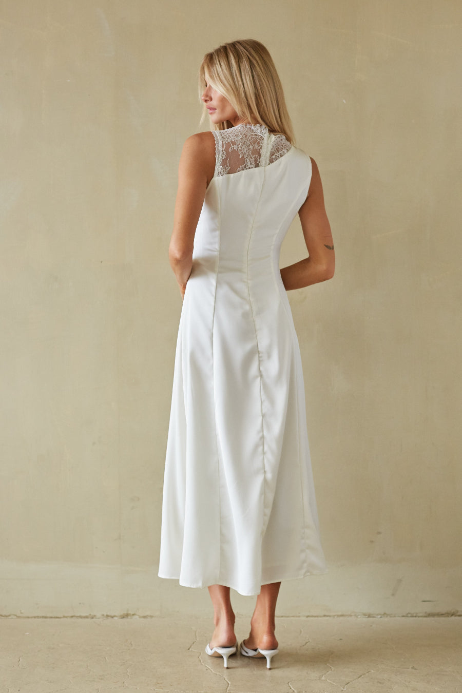 Woman wearing a white dress with lace detailing on a beige background