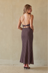 Brunette model wearing a brown and white polka dot dress against a beige background