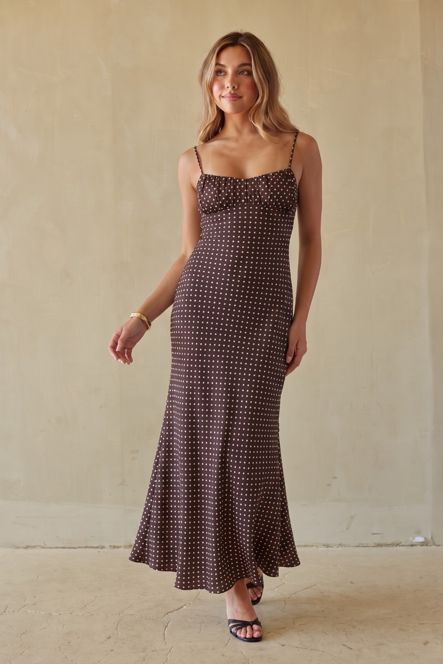 brown-image | Brunette model wearing a brown and white polka dot dress against a beige background